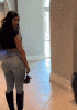 a woman in a black top and jeans is walking down a hallway .
