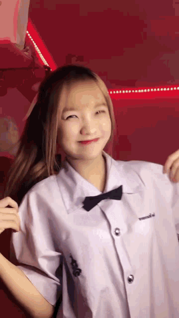a girl wearing a white shirt and a black bow tie is making a funny face