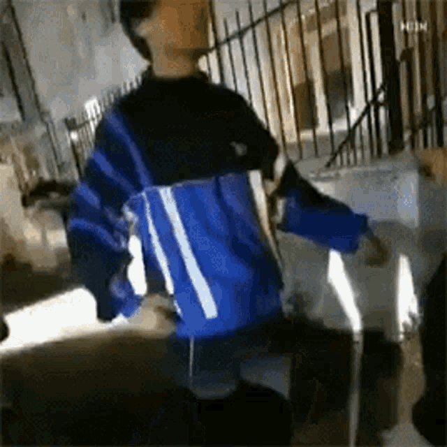a man in a blue and black jacket is standing on a sidewalk .
