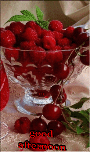 a glass bowl of raspberries and cherries with the words good afternoon on the bottom