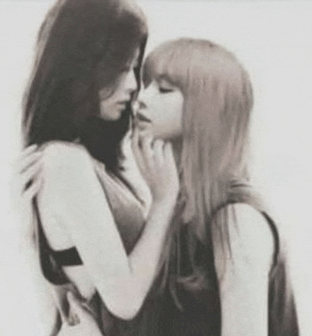 a black and white photo of two women kissing each other on the cheek .