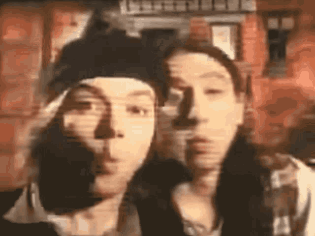 a blurry picture of two people standing next to each other in front of a brick building