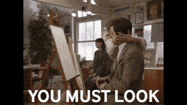 a man in a suit is being hugged by a woman in front of an easel with the words " you must look " above him