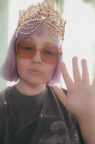 a woman with purple hair wearing sunglasses and a gold crown