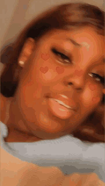 a close up of a woman 's face with red hearts on her face .