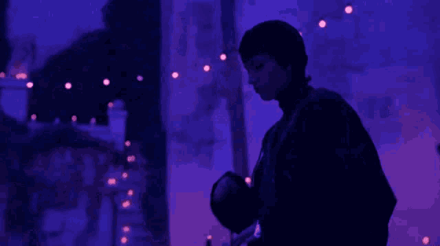 a man in a dark room with purple lights