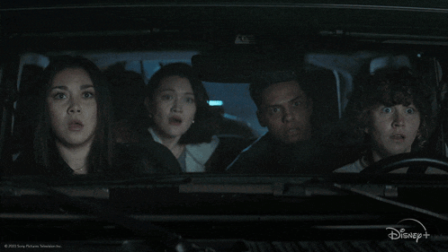 a group of people are sitting in a car with a disney logo on the bottom right