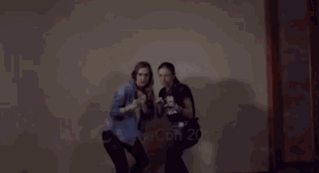 two women are dancing in front of a wall with the year 2019 written on it