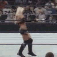 a woman is standing in a wrestling ring with a crowd behind her .