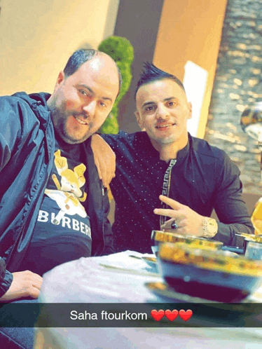 two men are posing for a picture and one has a shirt that says burberry on it