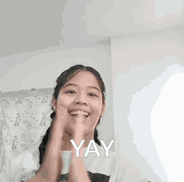 a girl is smiling and holding her hands together with the word yay written below her