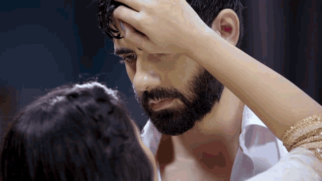 a man with a beard and a woman touching his forehead
