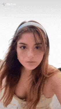 a woman wearing a headband and a plunging neckline is looking at the camera .
