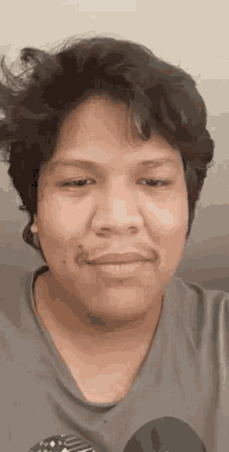a man with a mustache is making a funny face while wearing a gray shirt .