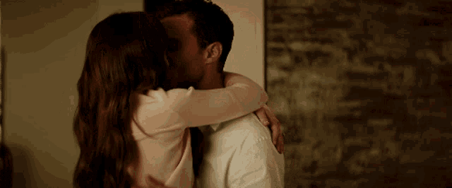 a man and a woman kissing in front of a wall
