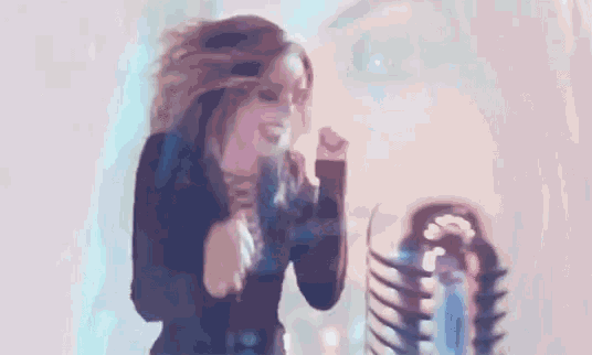 a woman is dancing in front of a microphone with a skeleton in the background .