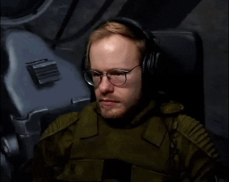 a man wearing headphones and glasses is sitting in a chair and asking what is that ?