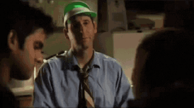 a man wearing a green hat and a tie is talking to another man .