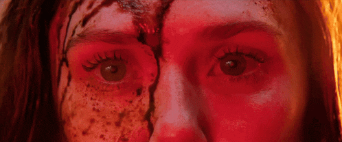 a close up of a woman 's eyes with red paint on them