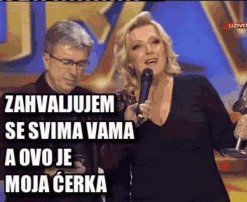 a woman singing into a microphone while a man watches