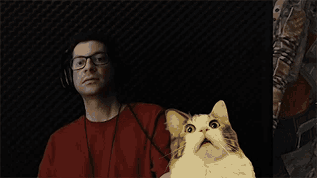a man wearing headphones is holding a cat