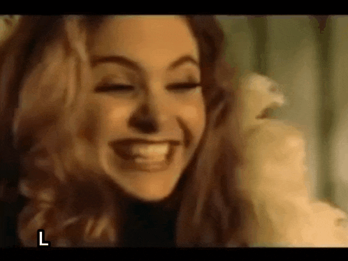 a close up of a woman smiling with her eyes closed and a bird in her hand .