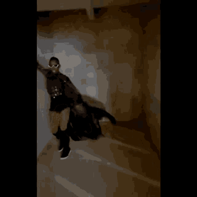 a woman in a black dress is standing on a set of stairs in a room .