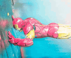 a toy of iron man is leaning on a blue wall