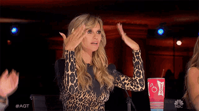 a woman in a leopard print top is clapping in front of a cup that says sonic on it