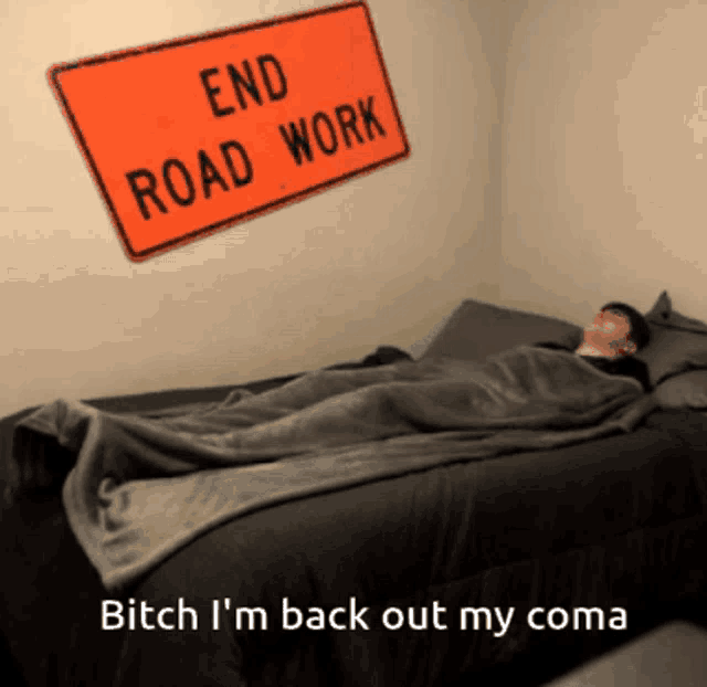 a man is laying on a bed under a sign that reads end road work