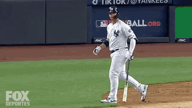 a new york yankees baseball player is walking towards home plate
