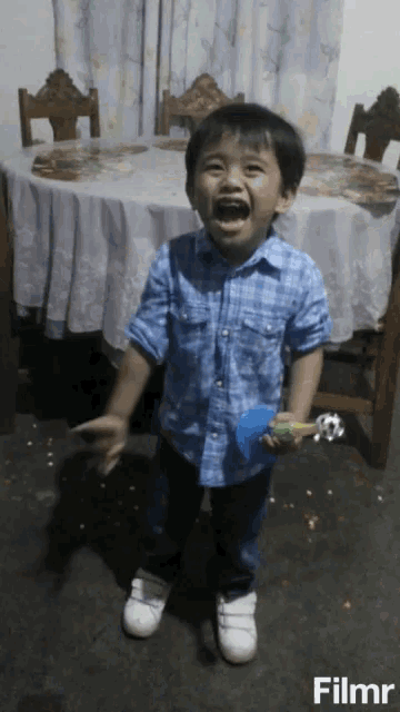 a young boy standing in front of a table with a filmr watermark