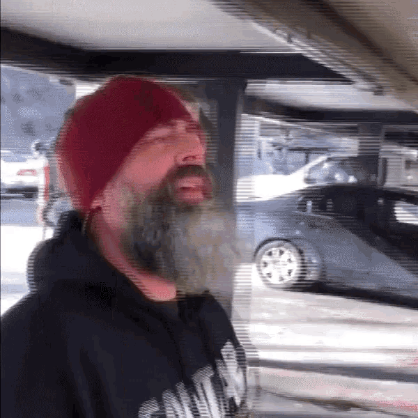 a man with a beard wearing a red hat and a sweatshirt that says ' santa ' on it
