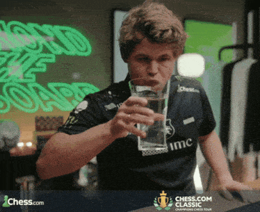 a man drinking a glass of water from a chess.com classic champions chess tour