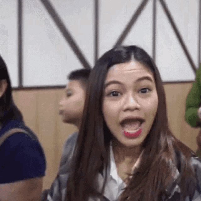 a woman making a funny face with her mouth open in front of a group of people