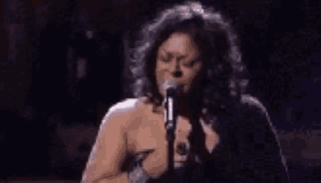 a woman is singing into a microphone while standing on a stage .