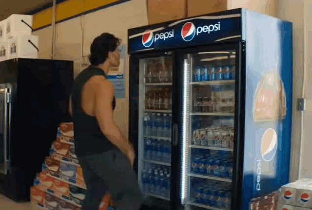 a man standing in front of a pepsi refrigerator