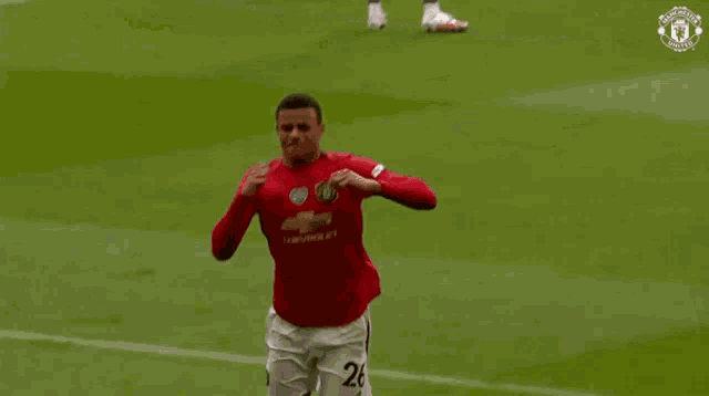 a soccer player in a red shirt is kneeling on the field while celebrating a goal .
