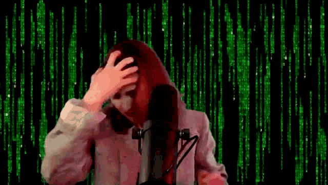 a woman is singing into a microphone in front of a green background with numbers .