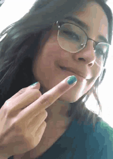 a woman wearing glasses and a blue shirt is giving the middle finger
