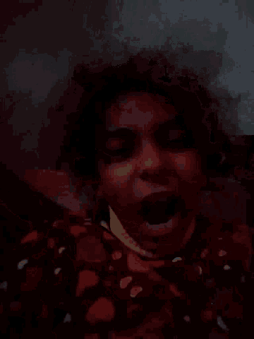 a close up of a woman 's face with curly hair in the dark .