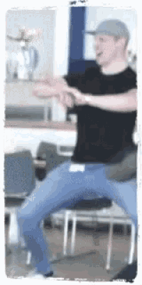 a man in a black shirt is sitting on a chair with his legs crossed