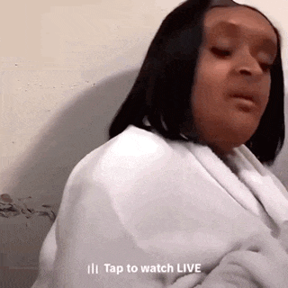 a woman in a white robe is sitting on a bed and talking to someone .