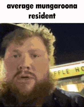 a man with a beard stands in front of a sign that says waffle house