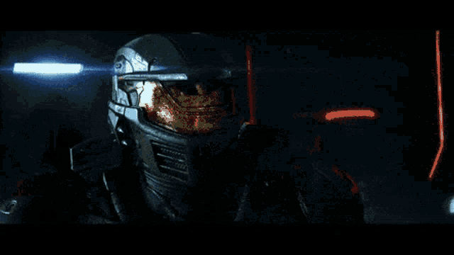 a man in a helmet stands in a dark room with a light behind him