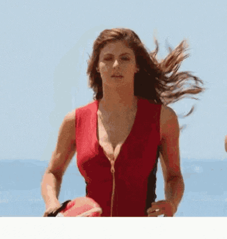 a woman in a red swimsuit is holding a life preserver on the beach .