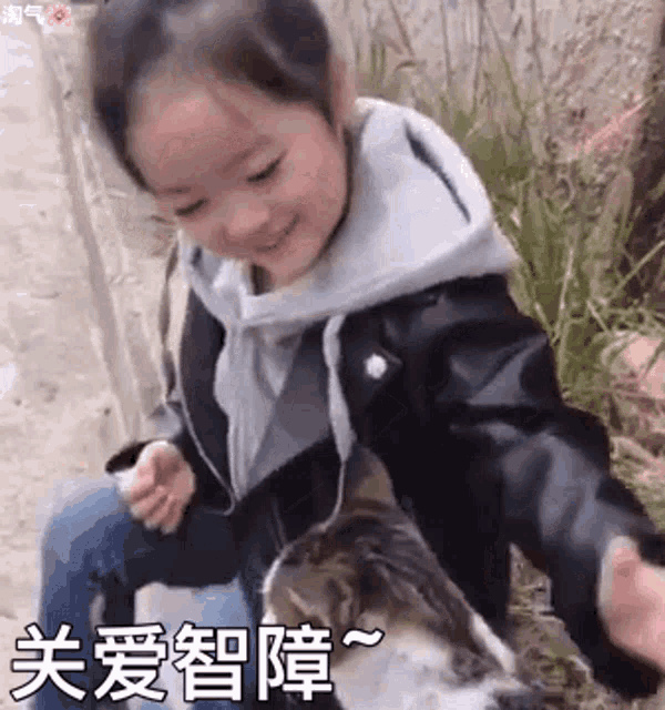 a little girl is petting a cat in a field .