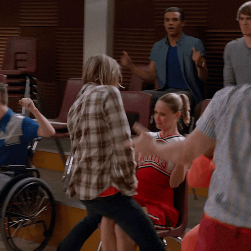 a cheerleader wearing a uniform that says ' bulldogs ' on it talks to a man in a wheelchair
