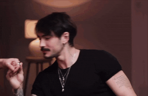 a man with a tattoo on his arm has a ring in his finger