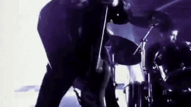 a man is playing a guitar in front of a drum set .